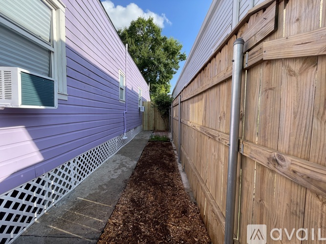 A narrow alley between two buildings with a wooden fence on the right.