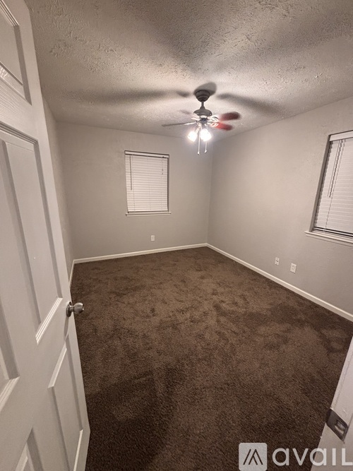 A room with a carpeted floor and a ceiling fan.
