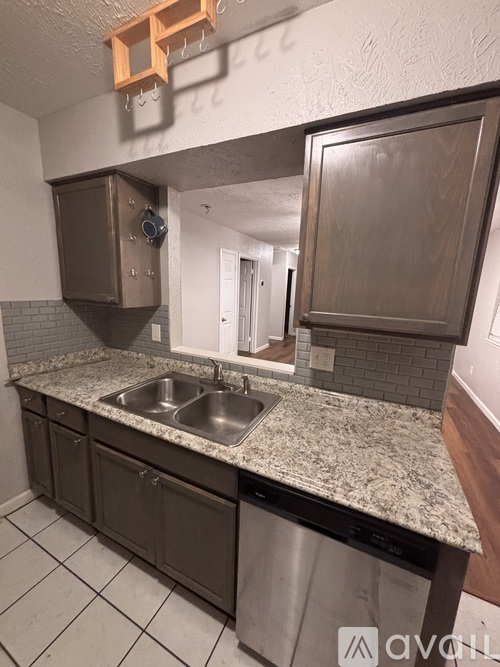 A kitchen with a granite countertop and a stainless steel dishwasher.