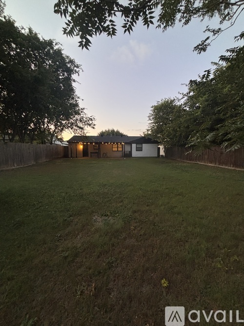 A backyard with a house and a fence.