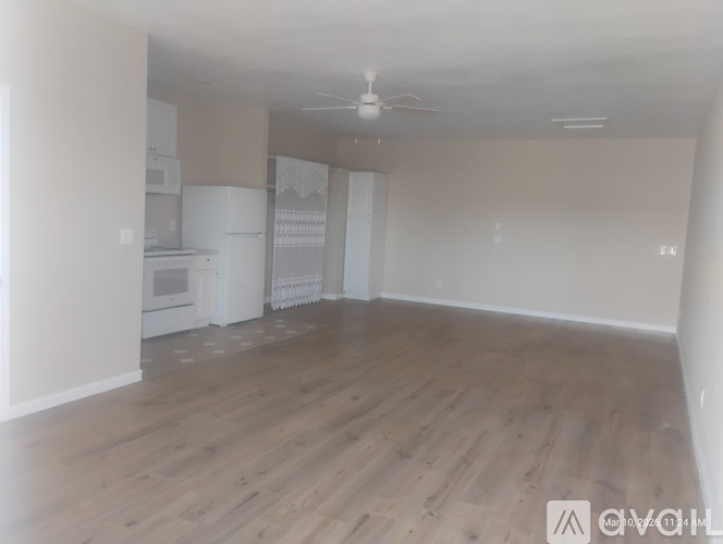 A spacious room with wooden flooring and a ceiling fan.