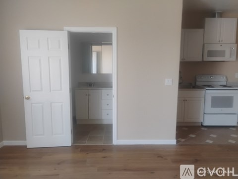 A kitchen with white appliances and cabinets is visible through an open door.