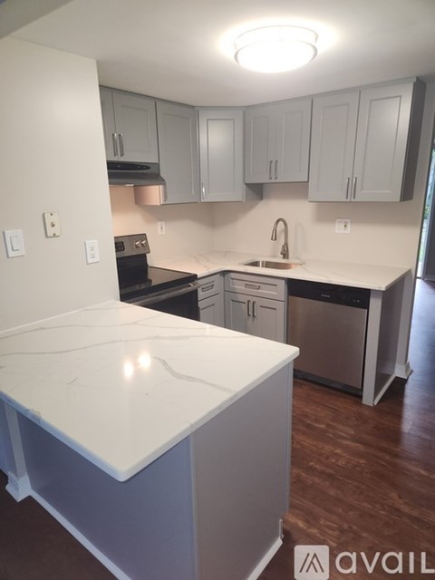 A kitchen with a white counter top and grey cabinets.