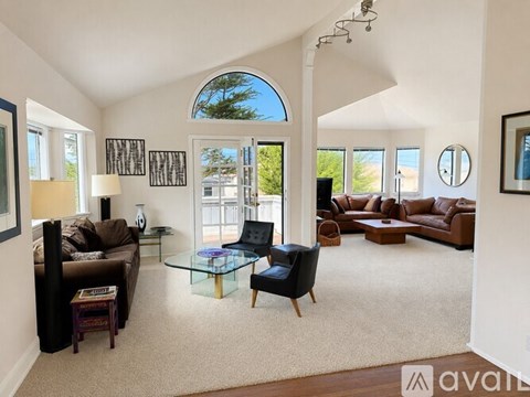 A living room with a glass coffee table and a brown couch.