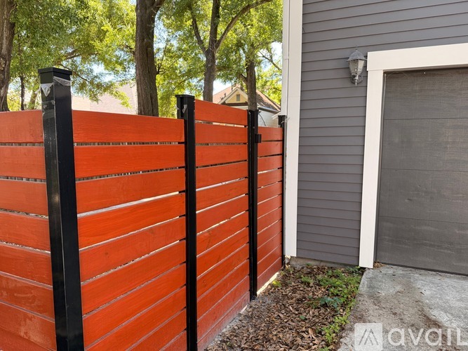 A wooden fence with black posts and a grey house in the background.