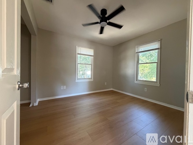 A room with a ceiling fan and two windows.