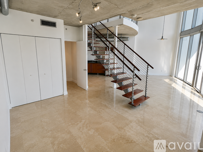A spacious room with a staircase and a large window.