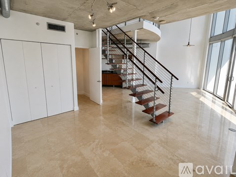 A spacious room with a staircase and a large window.