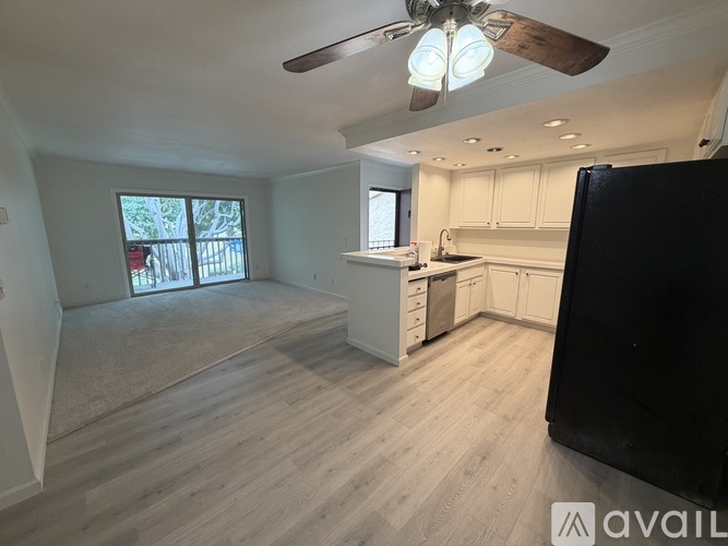 A kitchen with white cabinets and a black refrigerator.