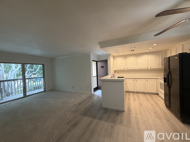 A kitchen with white cabinets and a black refrigerator.