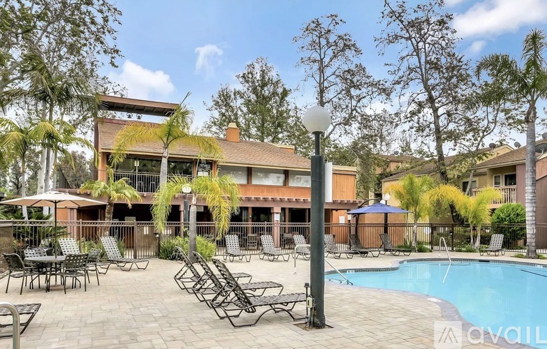 A poolside area with chairs and a building in the background.