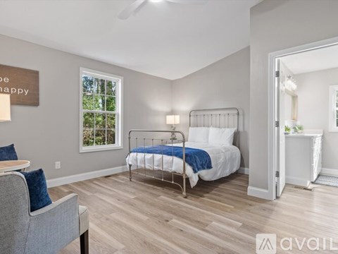 A bedroom with a bed, chair, and window.