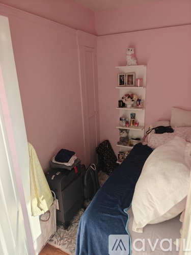 A small bedroom with a bed, a dresser, and a shelf with various items on it.