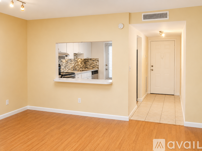 A room with a window showing a kitchen and a door on the right.