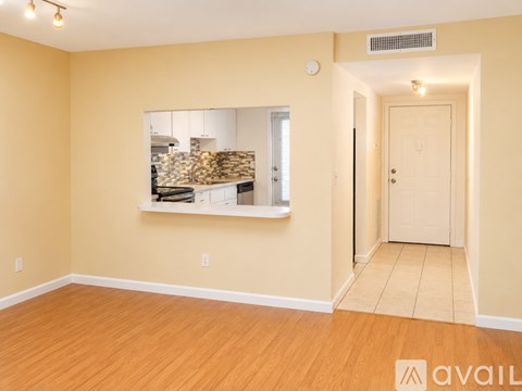 A room with a window showing a kitchen and a door on the right.