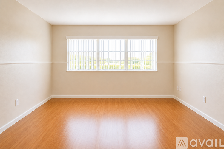 A room with wooden floors and a window with blinds.