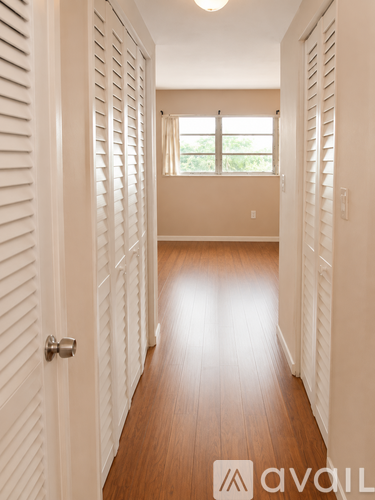 A hallway with white walls and wood floors.