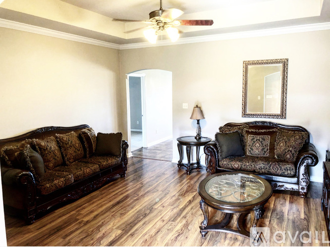 A living room with a brown couch and a glass coffee table.