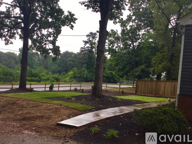 A backyard with a tree, a fence and a grassy area.