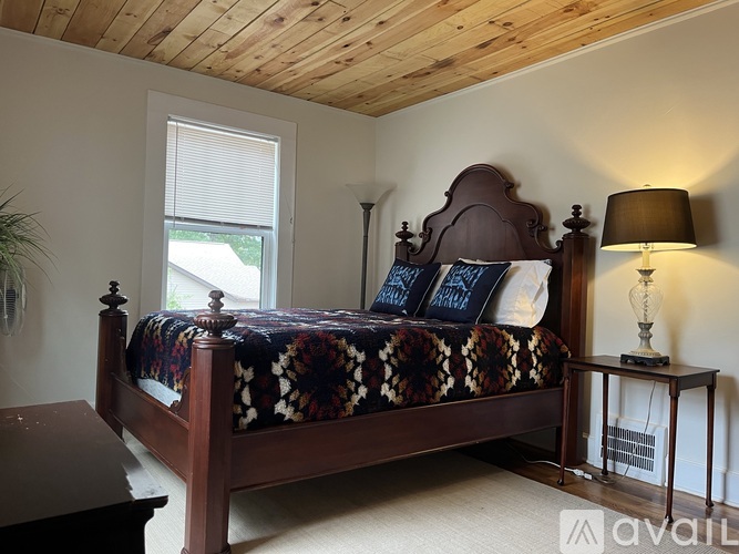 A bedroom with a large bed and a wooden ceiling.