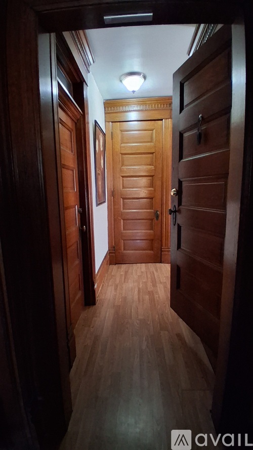 A long hallway with wooden doors and a light on the wall.