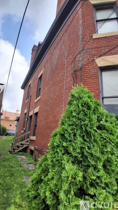 A red brick building with a tree in front.