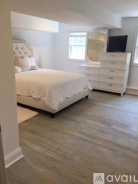 A bedroom with a large bed, a dresser, and a television.
