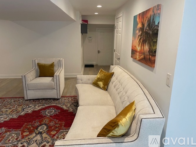A living room with a white couch and a red patterned rug.