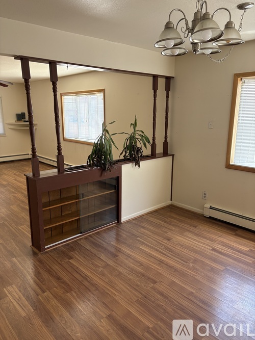 A room with wooden floors and a long wooden table with plants on it.