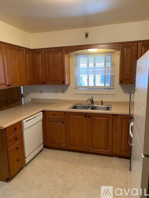 A kitchen with wooden cabinets and a white dishwasher.