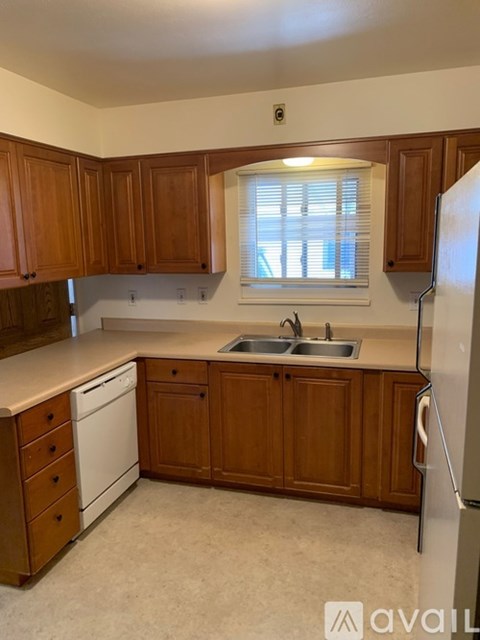 A kitchen with wooden cabinets and a white dishwasher.