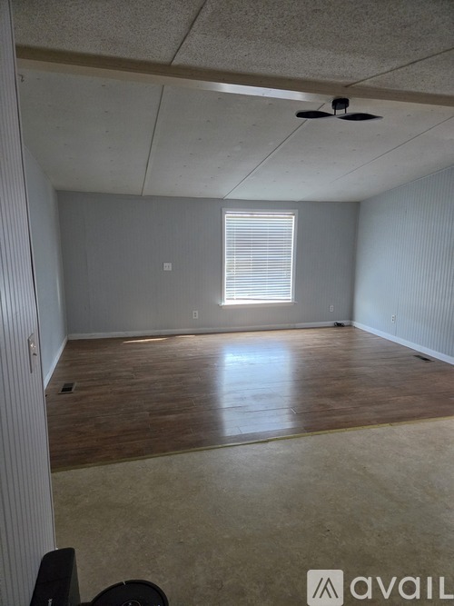 A room with a window and wooden flooring.