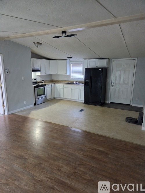 A kitchen with white cabinets and a black fridge.