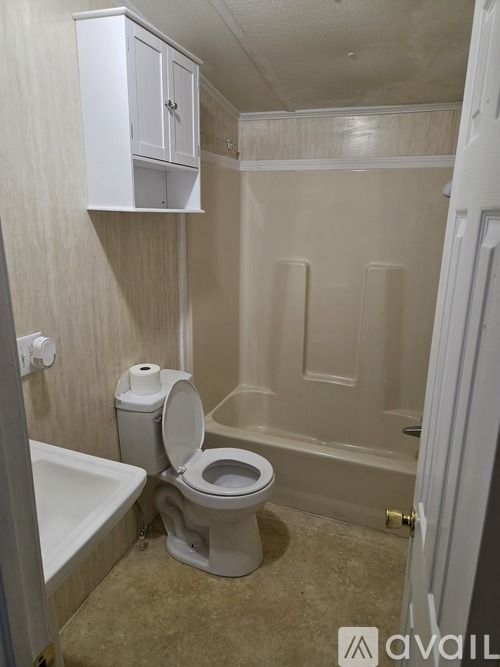 A white toilet is in a small bathroom with a white bathtub.