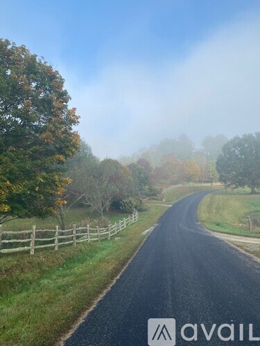 A road with a fence on the side and trees on both sides.