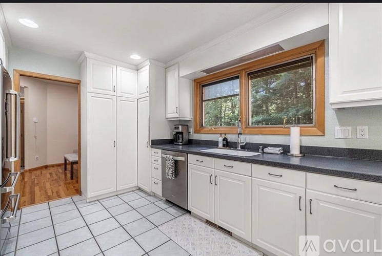 A kitchen with white cabinets and a black countertop.