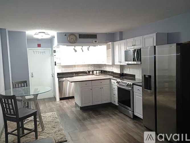 A kitchen with a glass table and a refrigerator.