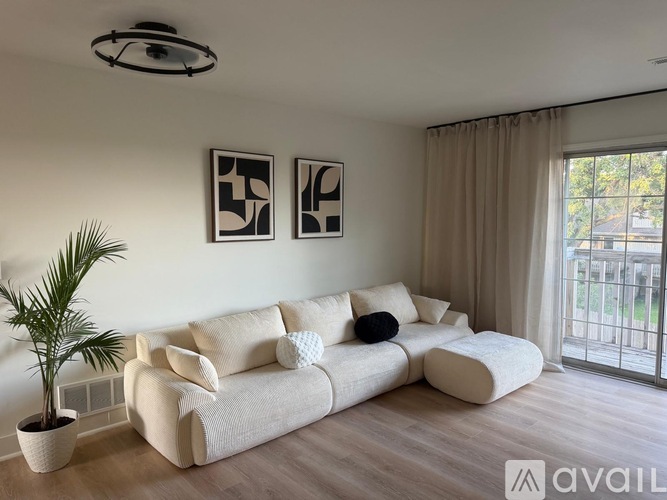 A living room with a white couch and two framed pictures on the wall.