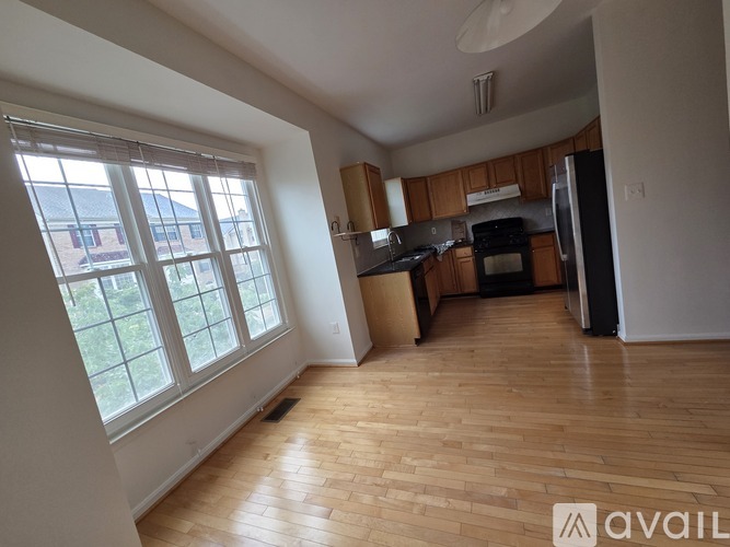 A kitchen with wooden floors and a window overlooking a yard.