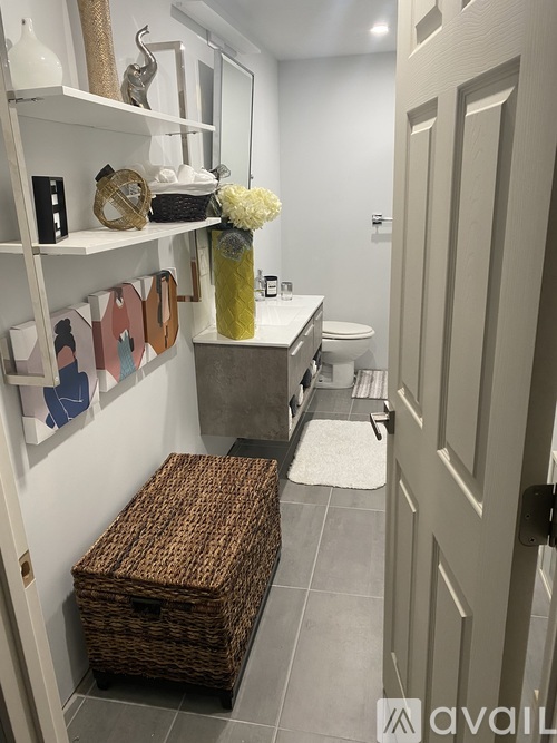 A bathroom with a toilet, sink, and a shelf with decorative items.