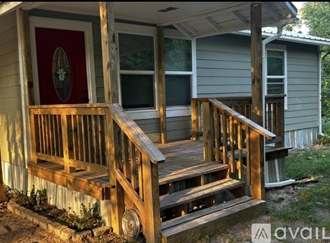 A wooden porch with a red door and a window.