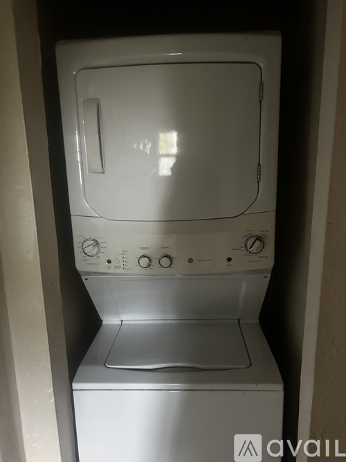 A white washing machine is sitting in a small space.