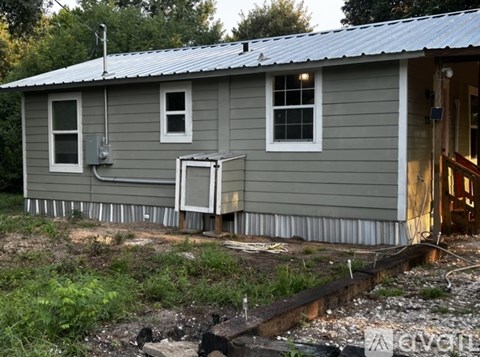 A house with a grey siding and a white window is shown.