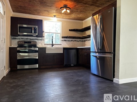 A kitchen with a wooden ceiling and a stainless steel refrigerator.