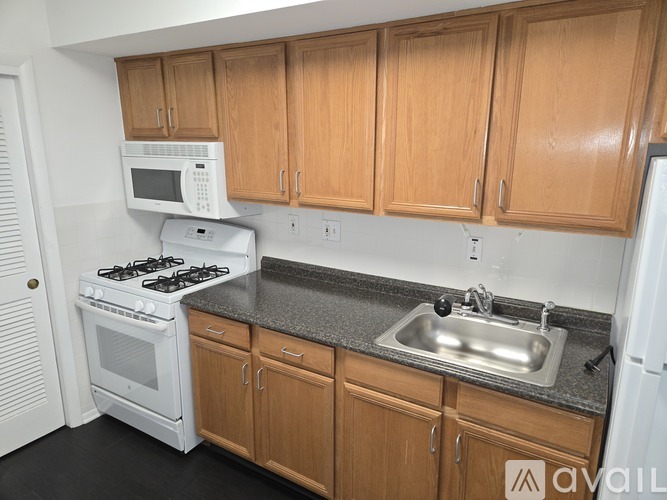 A kitchen with wooden cabinets and a white microwave above the stove.