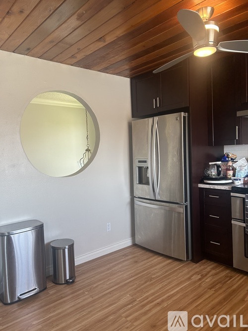 A kitchen with a stainless steel refrigerator and a round mirror on the wall.