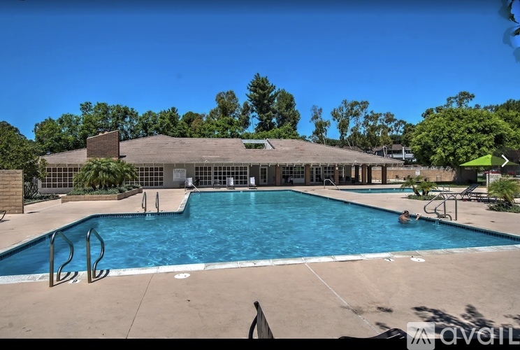 A large outdoor swimming pool with a diving board and a building in the background.