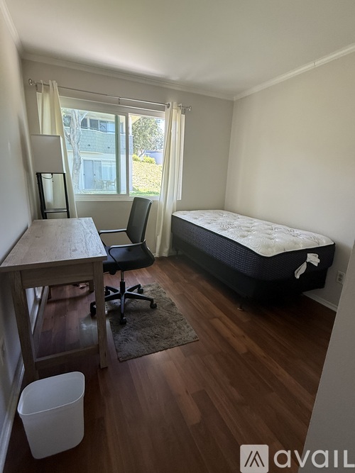 A bedroom with a bed, desk, chair, and window.