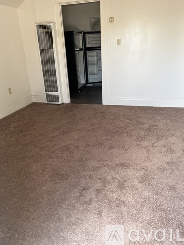 A room with a carpeted floor and a doorway leading to another room.