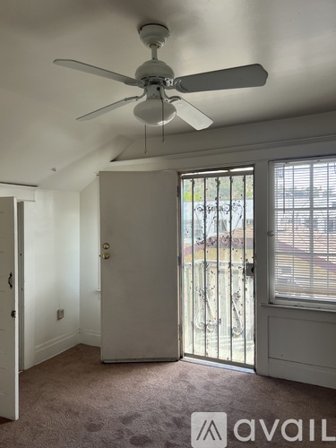 A room with a fan and a carpeted floor.